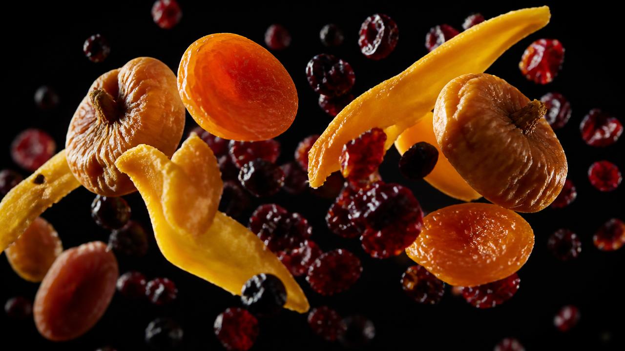 Dried figs, apricots, mango and berries suspended in dark studio light